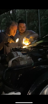 two men working on the hood of a car