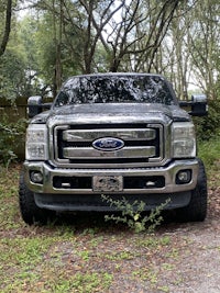 a silver ford super duty parked in the woods