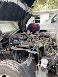 a man working under the hood of a truck