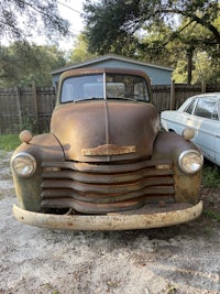 an old rusty truck is parked in a driveway