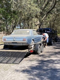 a ford mustang is being loaded onto a flatbed trailer