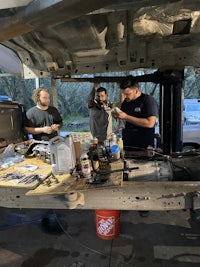 two people working on a vehicle in a garage