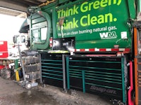 a green garbage truck with a sign that says think green think clean