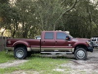a maroon truck parked in a wooded area